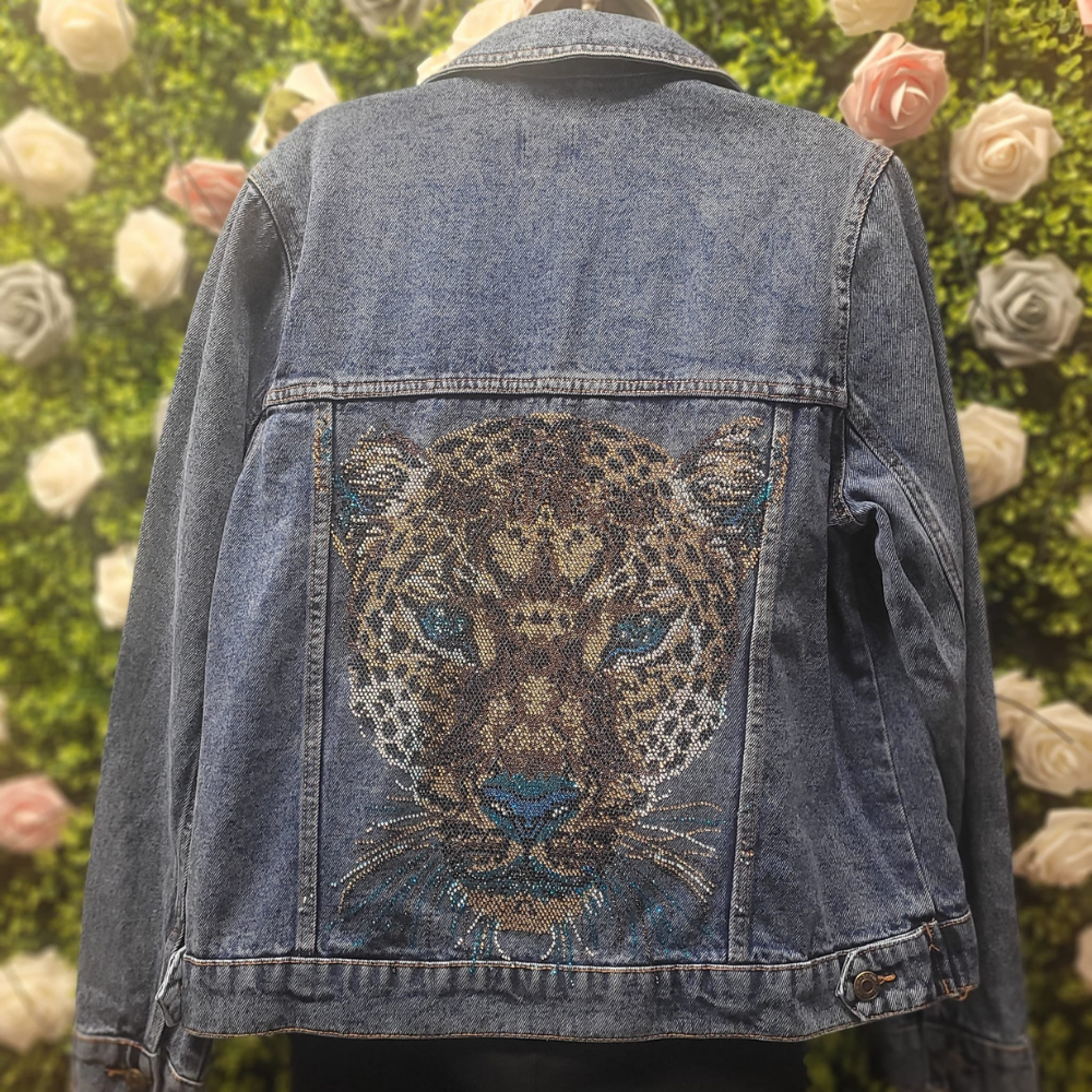 Denim jacket with a embroidered leopard design against a floral background