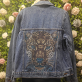 Denim jacket with a embroidered leopard design against a floral background