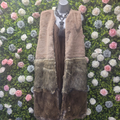Brown fur vest on a mannequin against a floral wall.
