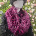 Mannequin wearing a black coat with a bright pink fur scarf against a blurred floral background