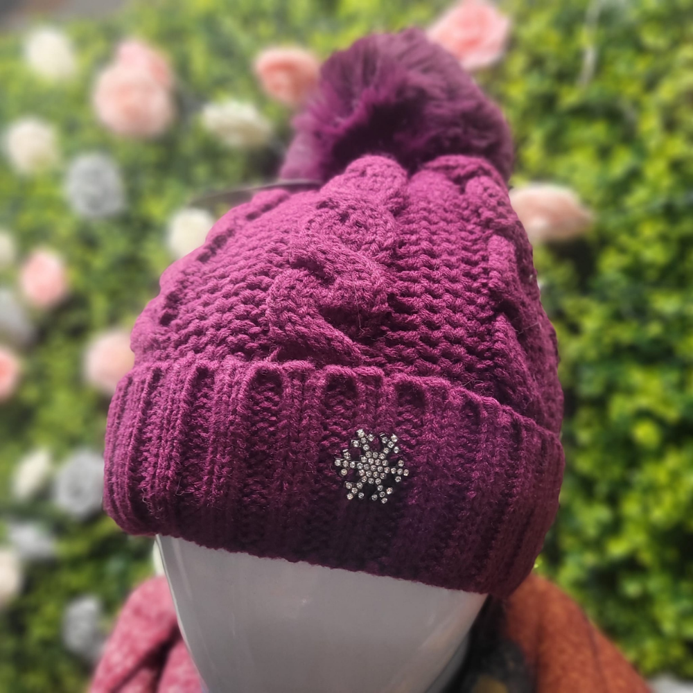Purple knitted beanie with a decorative snowflake on a blurred floral background