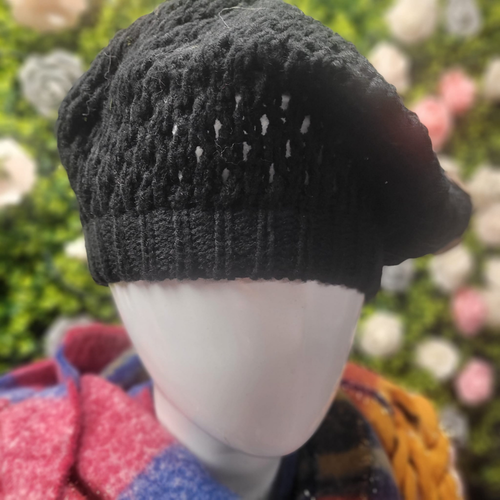 Black knitted beret on a mannequin head with a blurred floral background