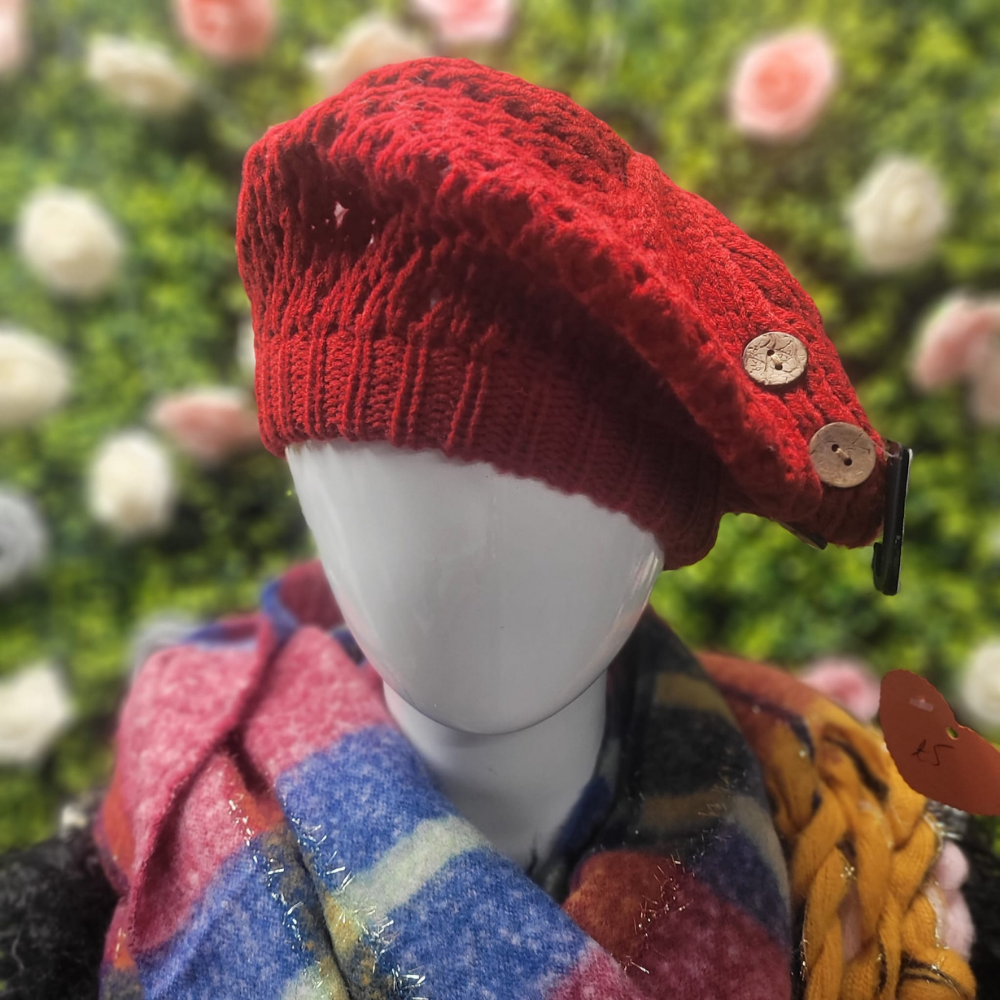 Red knitted beret with buttons on a mannequin against a floral background