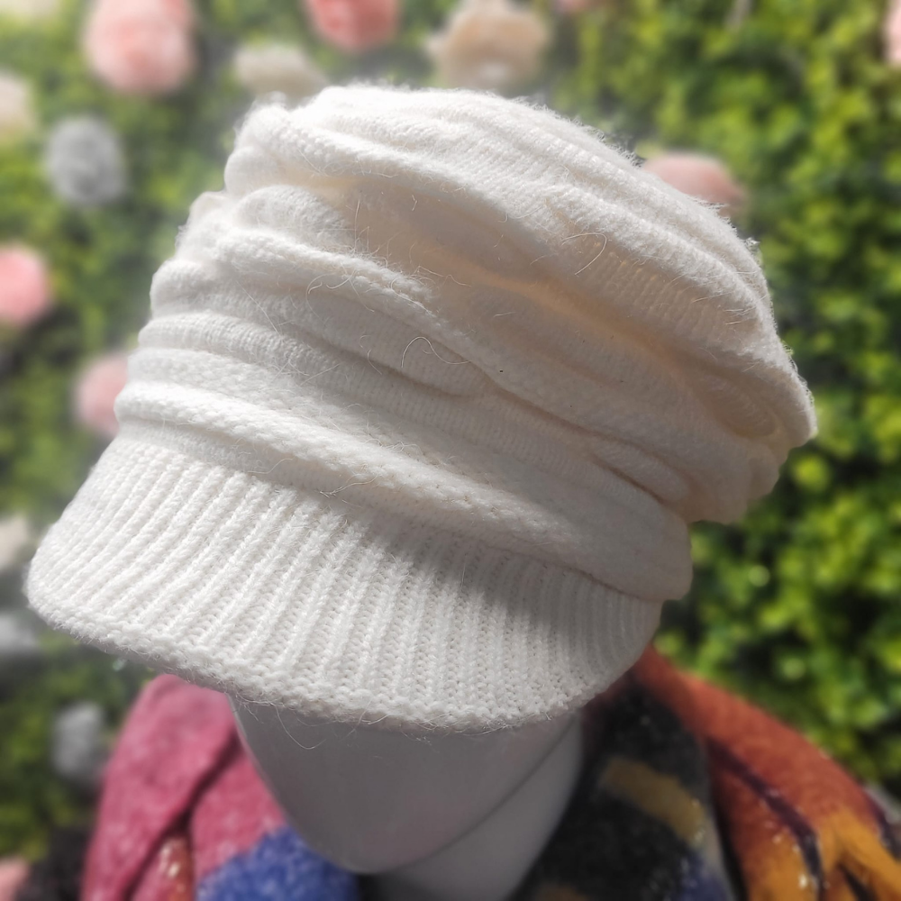 White knitted beanie on a mannequin head with a blurred floral background