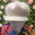 White knitted hat on a mannequin with a floral background