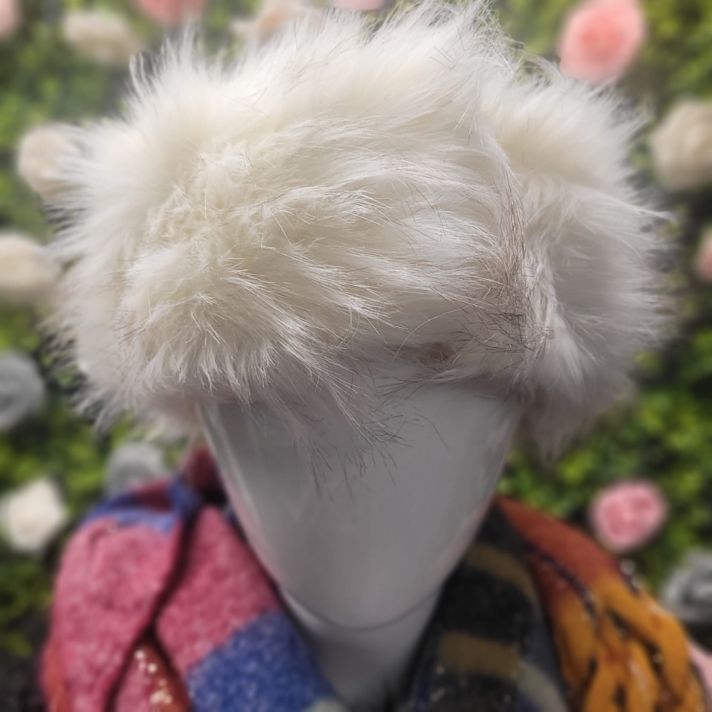 Mannequin head with white furry hat against a blurred floral background