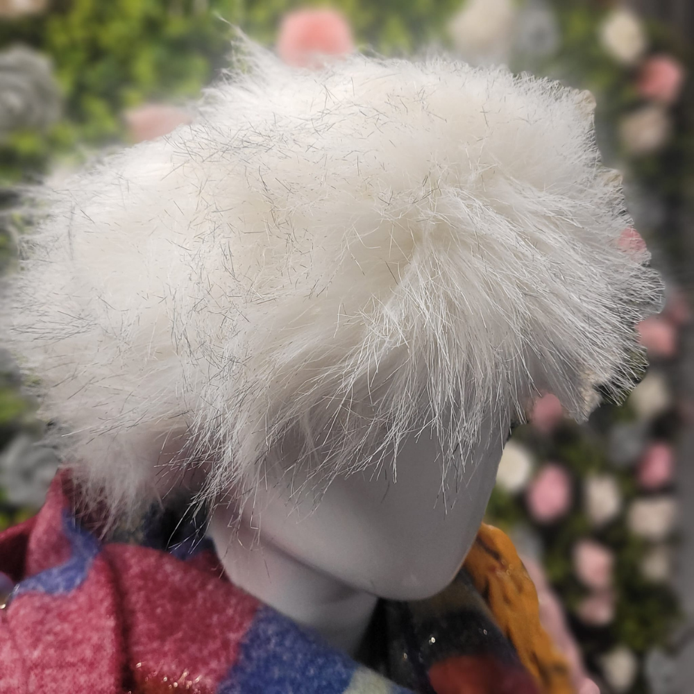Close-up of a mannequin head with a fluffy white hairpiece against a blurred floral background.