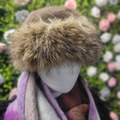 Mannequin head wearing a brown fur hat with a blurred floral background