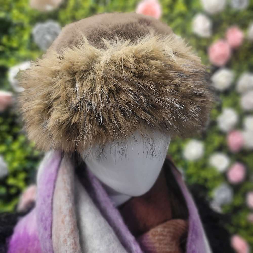 Mannequin head wearing a brown fur hat with a blurred floral background