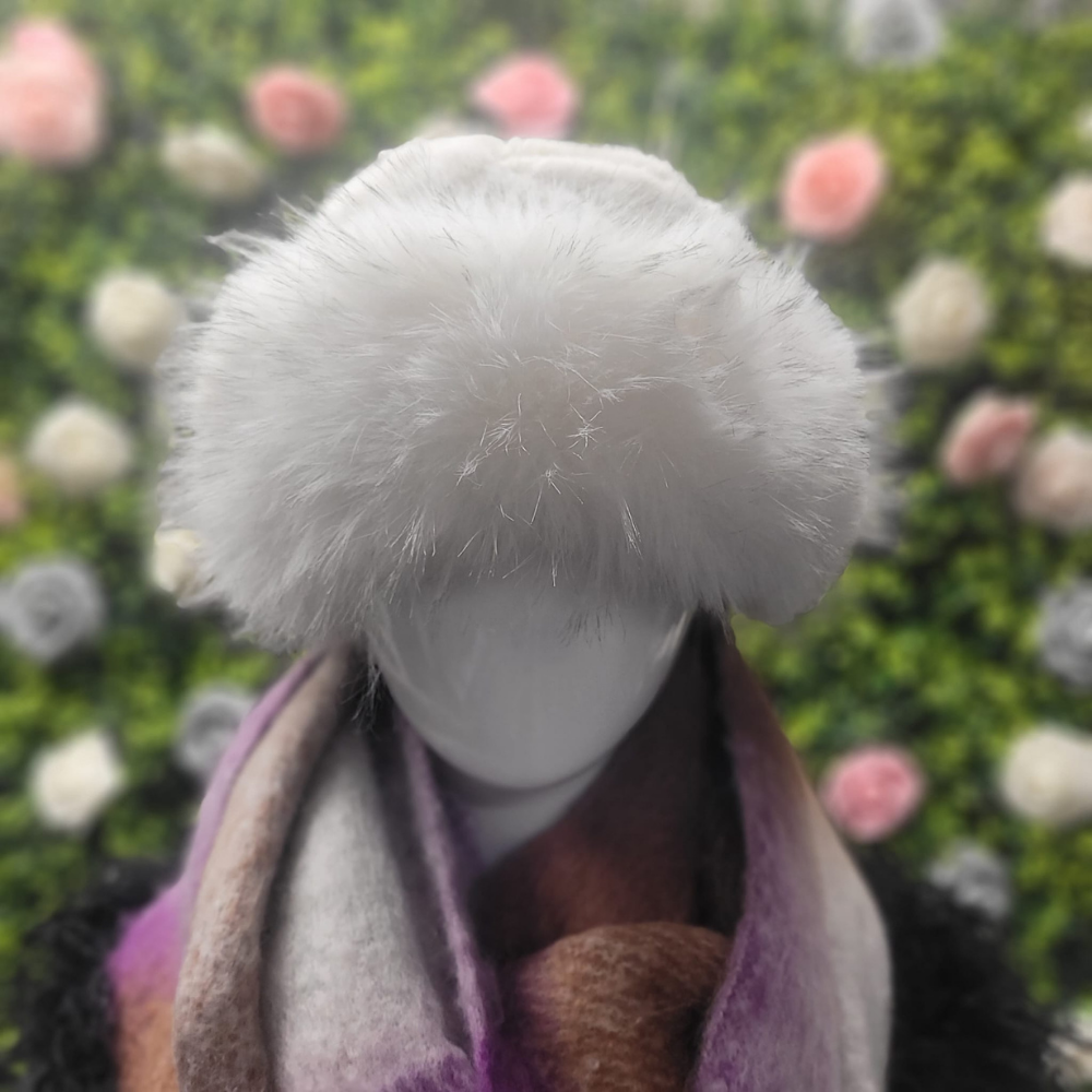 Mannequin head with a white fur hat and scarf against a blurred floral background