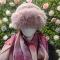 Mannequin wearing a pink fur hat and scarf with a floral background