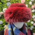 Mannequin head wearing a red furry hat with a blurred floral background