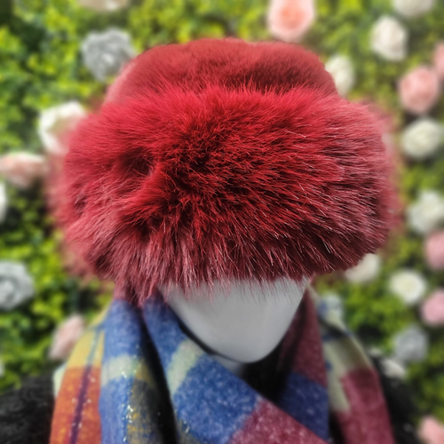 Mannequin head wearing a red furry hat with a blurred floral background