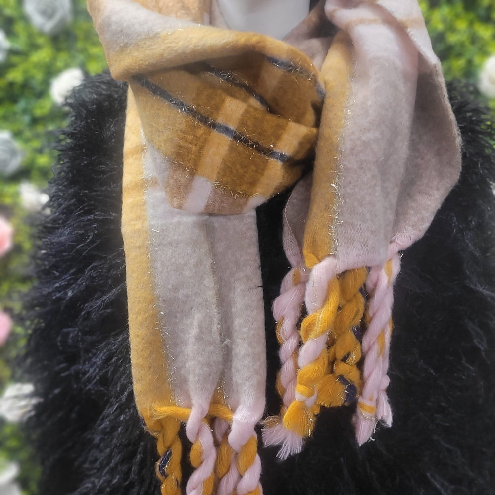 Pink and Mustard plaid scarf on a mannequin in front of a greenery wall 