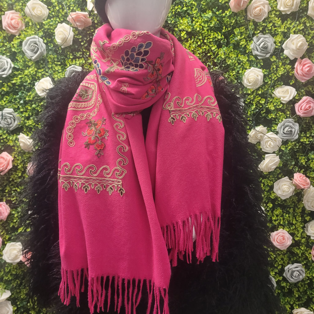 Pink scarf with intricate patterns on a mannequin against a floral background
