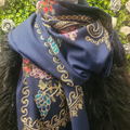 Blue scarf with intricate gold and multicolor patterns draped over a dark surface.