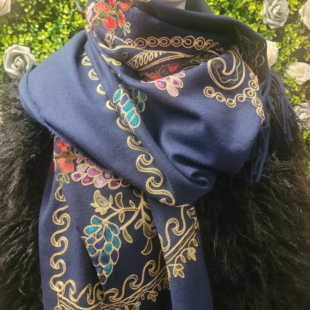 Blue scarf with intricate gold and multicolor patterns draped over a dark surface.