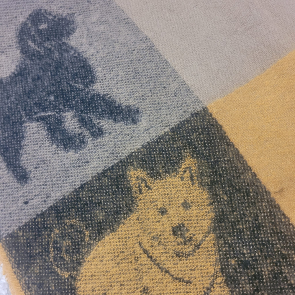 Close-up of a fabric scarf with dog pattern in various colours.