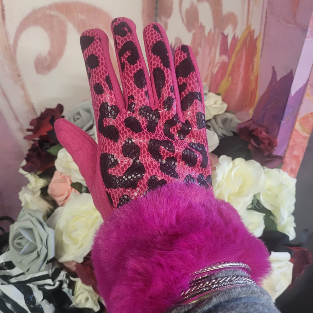 Pink gloves with black leopard print pattern worn by a person, against a floral background.