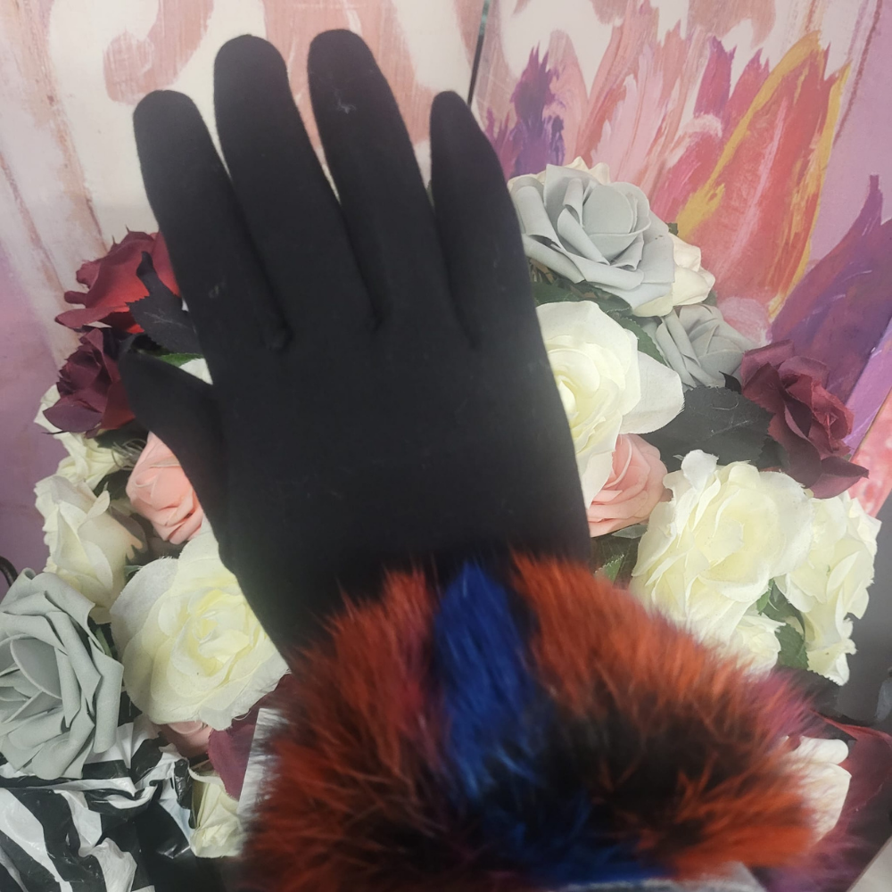 Black glove on a hand with colorful fur cuffs against a floral background