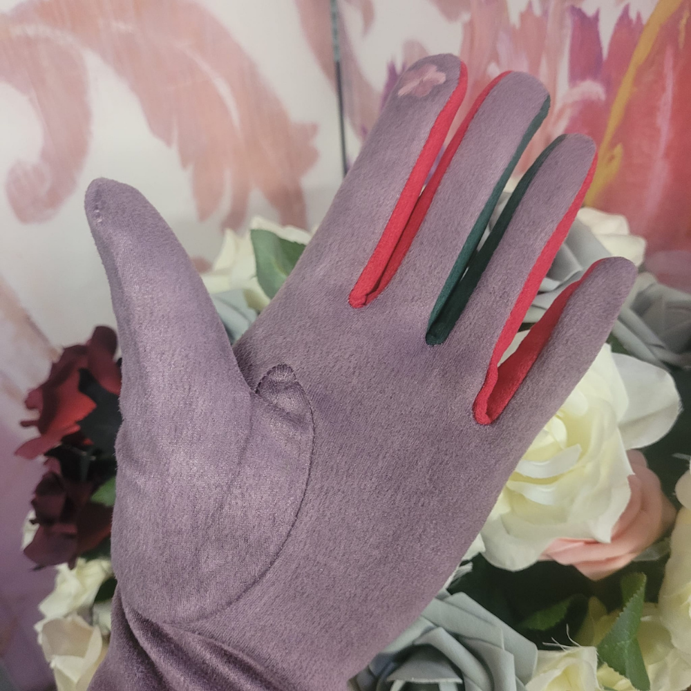Lilac glove with red and green accents worn by a person against a floral background