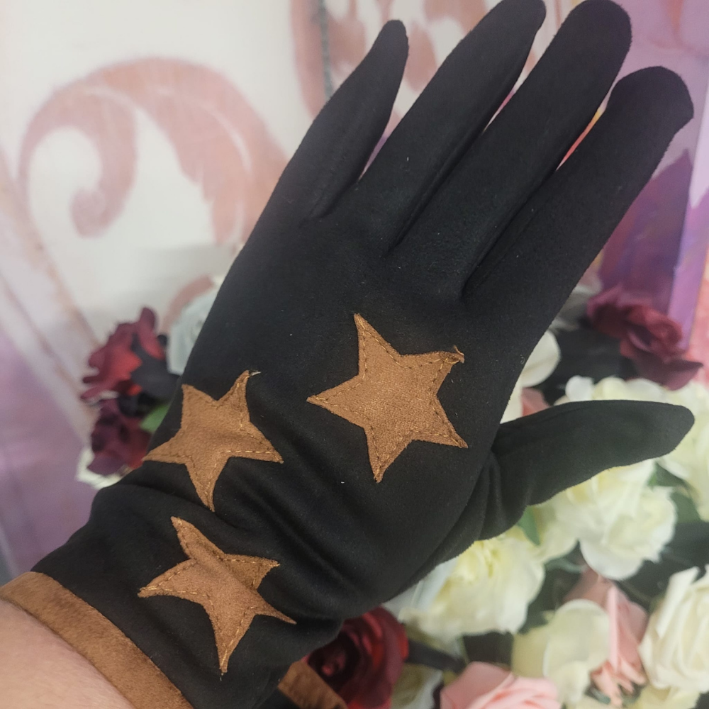 Black glove with brown star designs worn on a hand, against a floral background