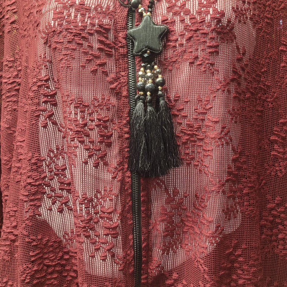 Decorative Lace Jacket with star and tassel on a greenery background