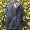 Blue textured cardigan with heart designs on a mannequin against a floral background