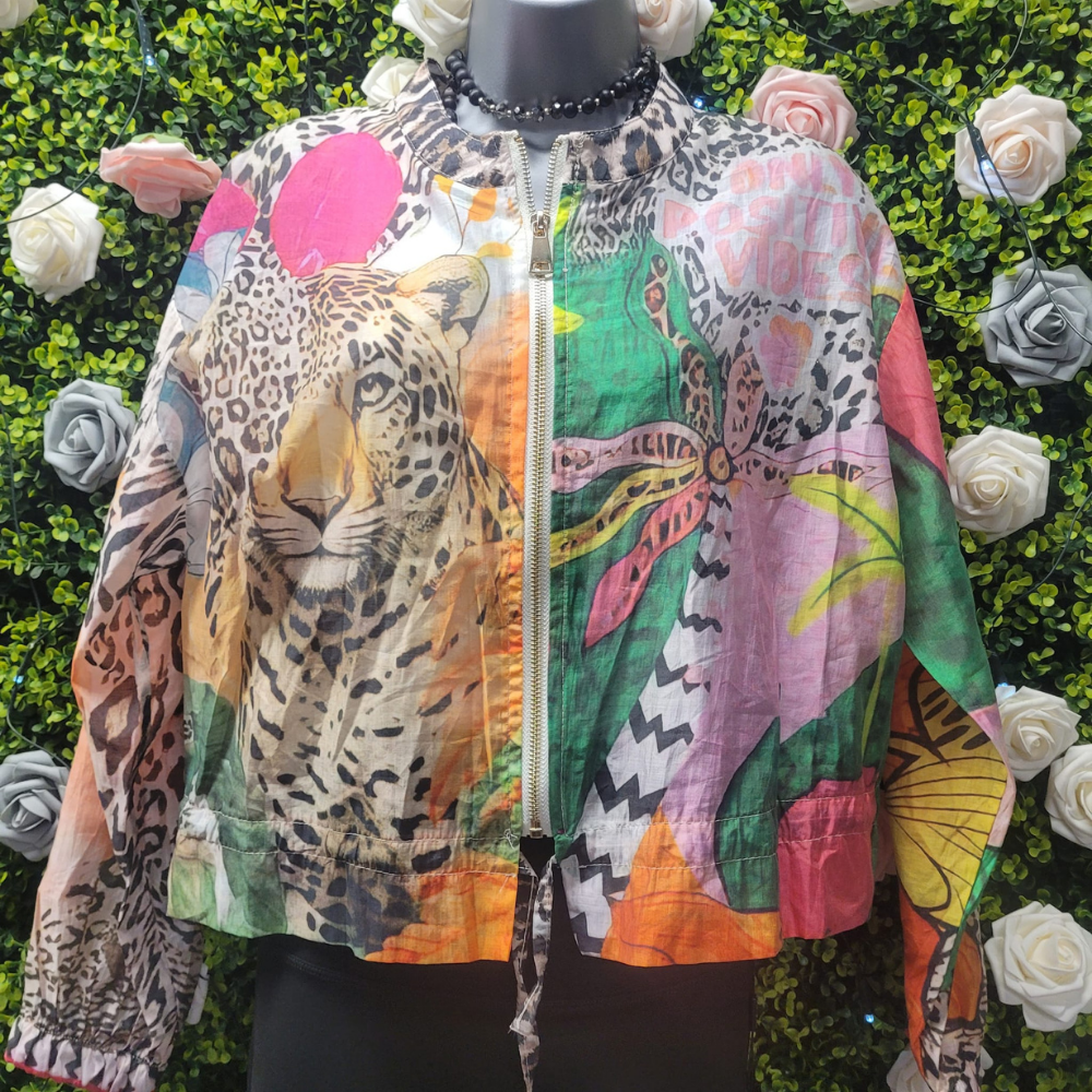 Colorful jacket with animal and floral patterns on a mannequin against a green leafy background.