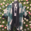 Midlength green tartan coatigan on a mannequin in front of a greenery wall