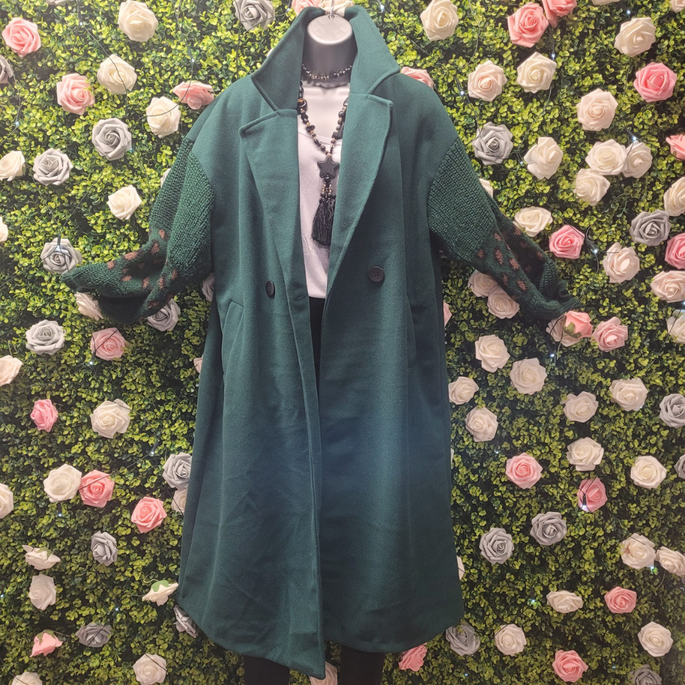 Green coat displayed on a mannequin against a floral wall.