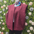 Maroon fleece vest on a mannequin against a floral background