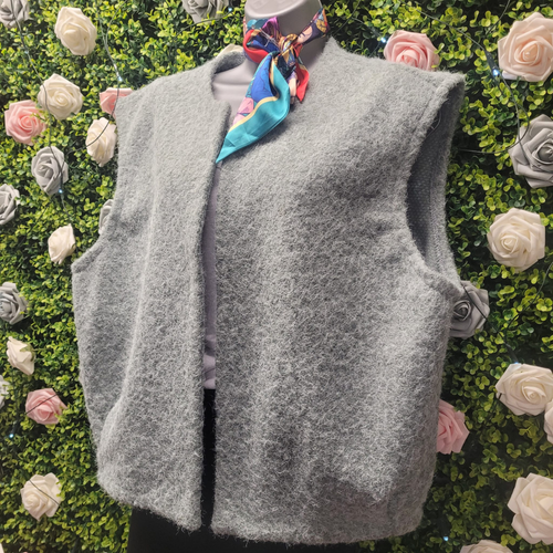 Grey Gilet on a mannequin in front of a greenery wall