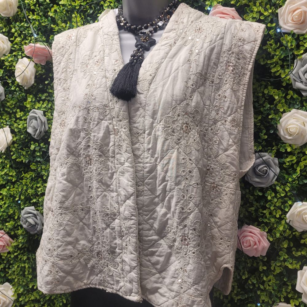 Quilted vest on a mannequin against a floral and greenery background