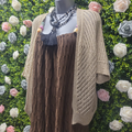 Gold cardigan shrug on a mannequin on a greenery backdrop
