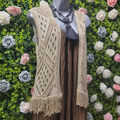 Gold crochet waistcoat on a mannequin with a greenery backdrop