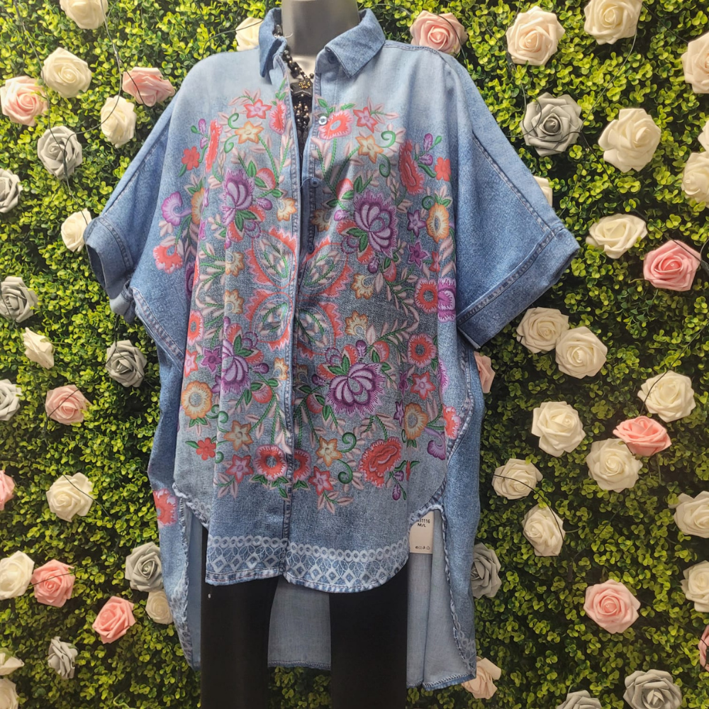 Blue floral embroidered shawl draped over a mannequin against a green wall with flowers