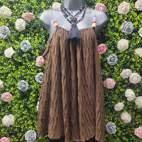Mannequin wearing a brown strappy vest top with a necklace against a floral background
