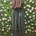 Khaki harem pants on a mannequin with a greenery backdrop