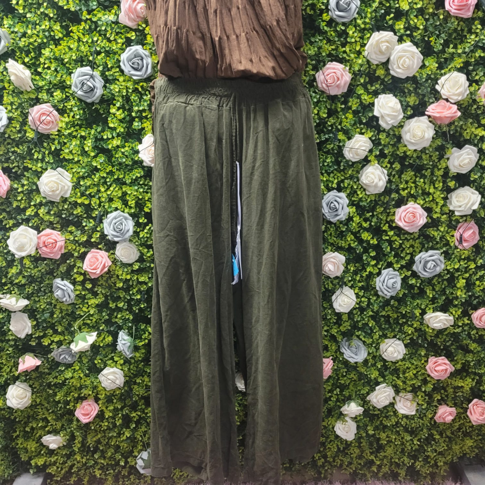Person wearing green pants standing against a green wall with floral decorations