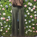 Person wearing green pants standing against a green wall with floral decorations