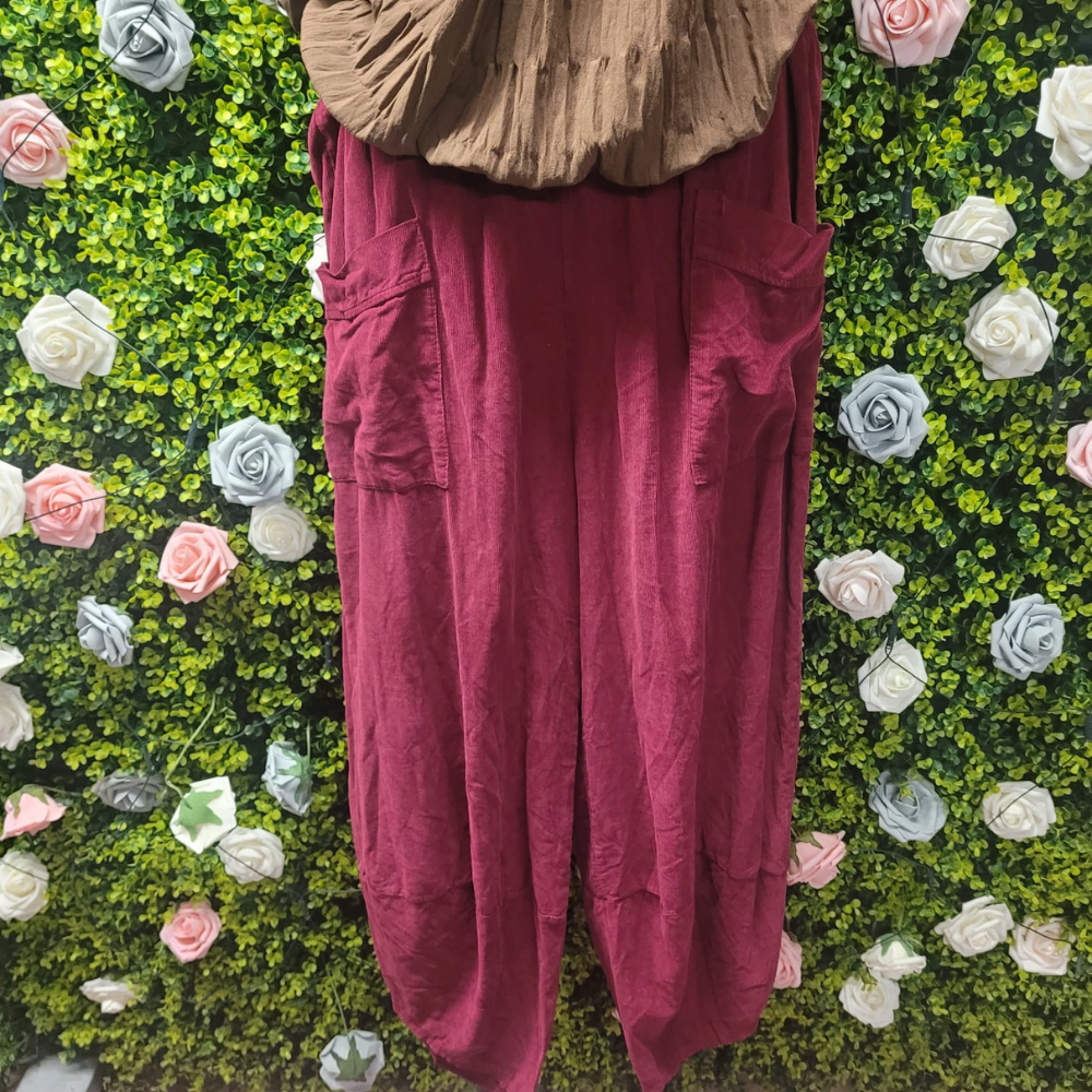 Wine coloured cord pants on a mannequin with a greenery backdrop