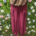 Wine coloured cord pants on a mannequin with a greenery backdrop