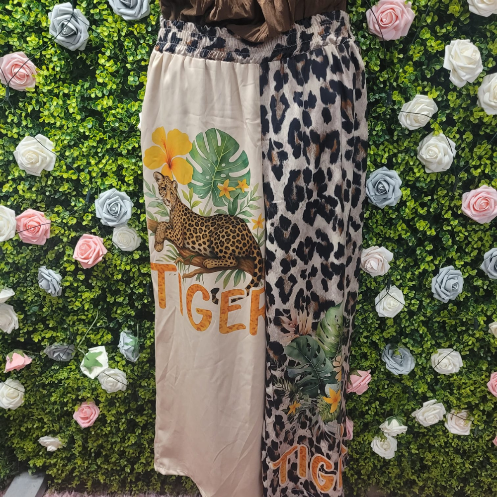 Pair of pants, one leg with a tiger design and one with leopard print, against a floral and green background.