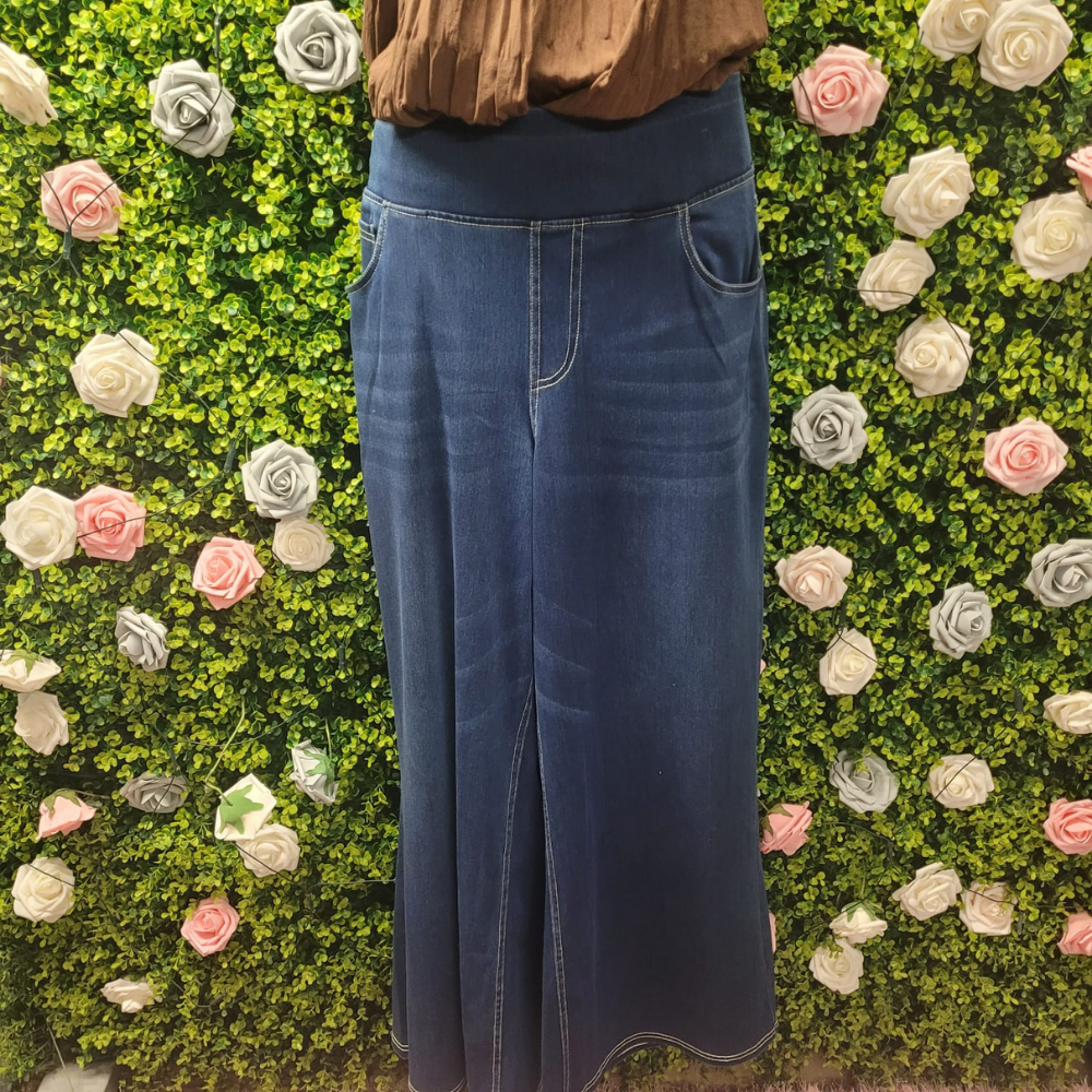 Person wearing blue jeans standing against a green wall with floral decorations